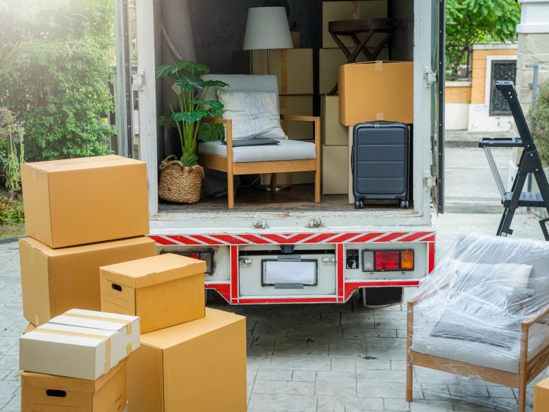Photograph of the open back of a moving truck with several fragile items and boxes waiting to be loaded inside.